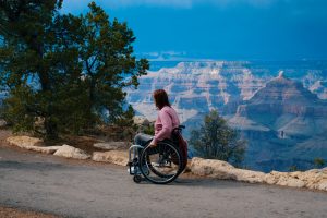 a woman in a wheel chair at the edge of a cliff