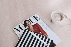 white capped pen on top of Vogue magazine beside cup of coffee