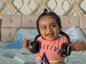 a little girl wearing headphones on top of a bed